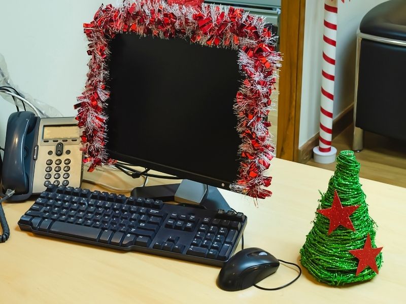 An office computer monitor draped in garland